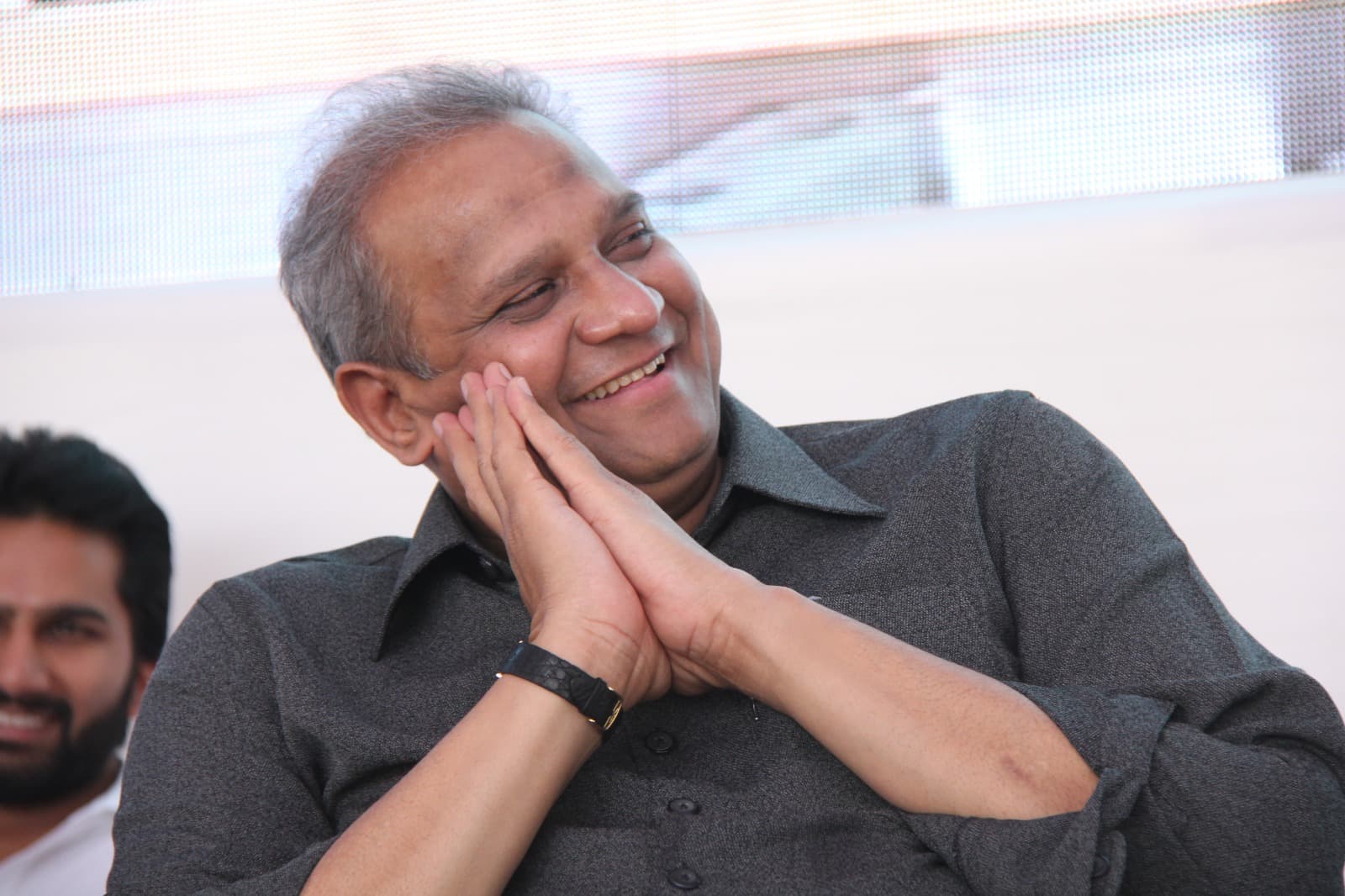 Bhupeshbhai resting his cheek on his hands, smiling during a public event